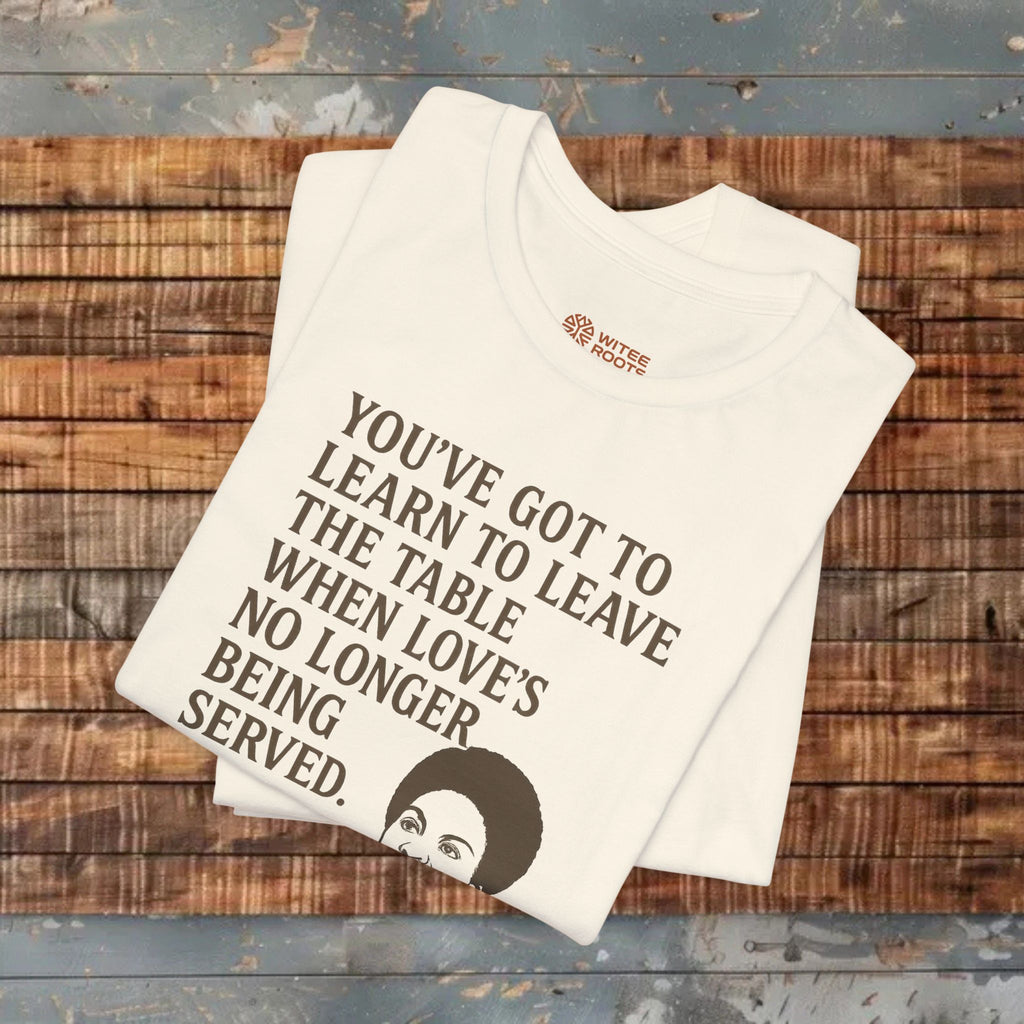 Beige t-shirt with text and graphic on a wooden surface