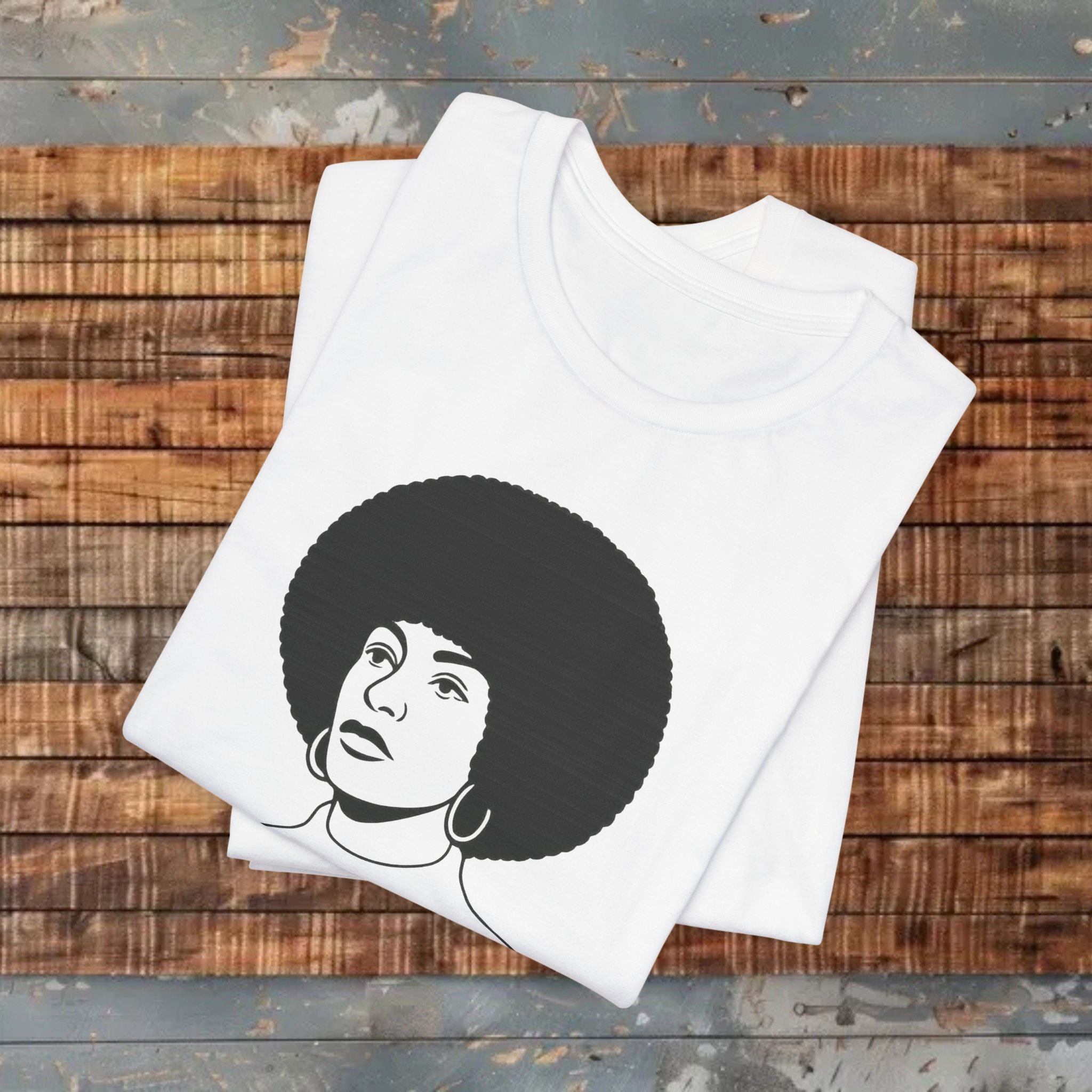 White tank top with a black and white graphic of a person with an afro on a wooden surface.