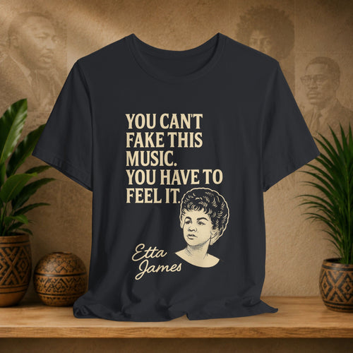 Black t-shirt with Etta James quote on a wooden surface with plants and a vintage-style background