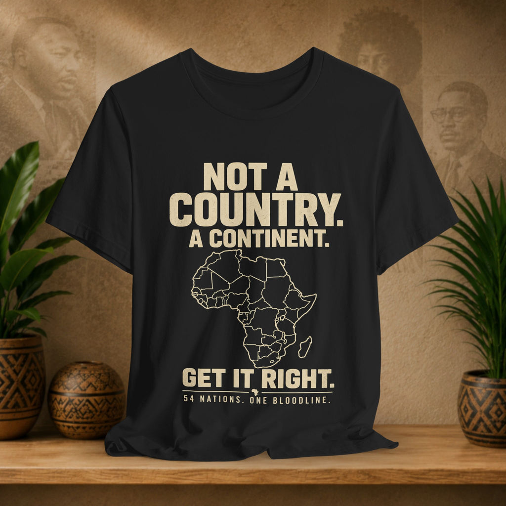 Black t-shirt with text and Africa map on a wooden surface with plants and decorative items.