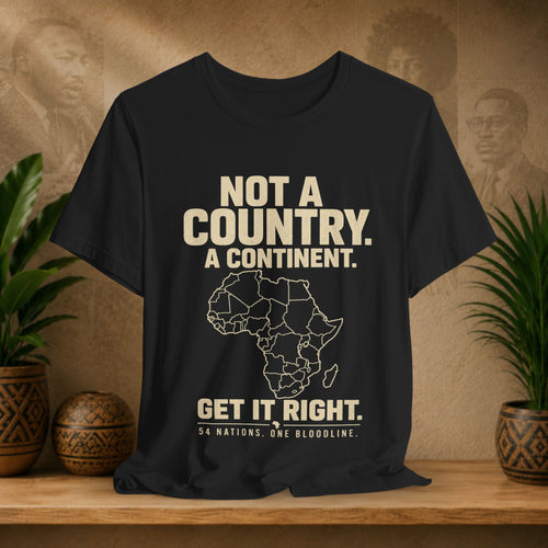 Black t-shirt with text and Africa map on a wooden surface with plants and decorative items.