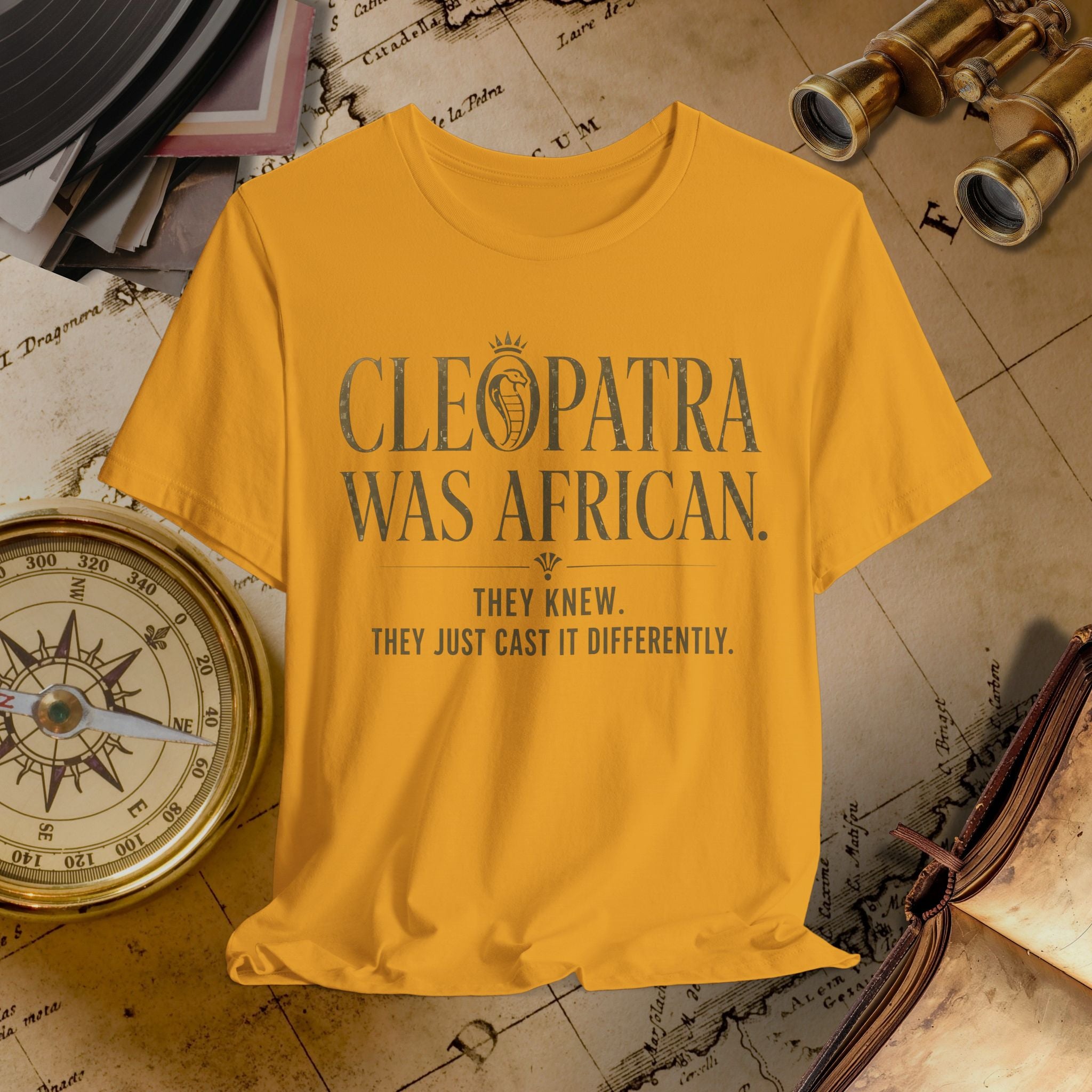 Mustard t-shirt with 'Cleopatra Was African' text on a historical-themed background