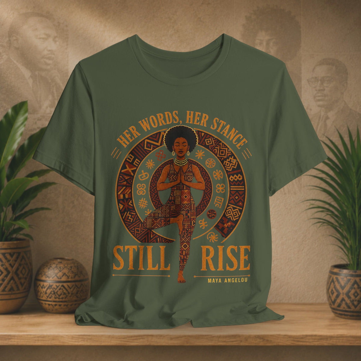 An olive green graphic t-shirt featuring a circular design with a woman in a yoga pose and the text 'HER WORDS. HER STANCE STILL RISE' and 'MAYA ANGELOU'.