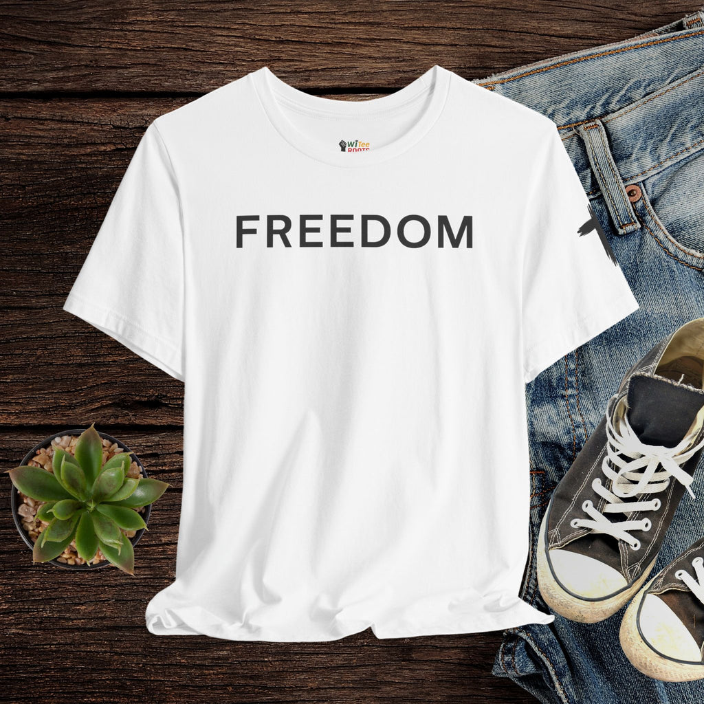 White t-shirt with 'FREEDOM' text on a wooden surface with jeans and sneakers.