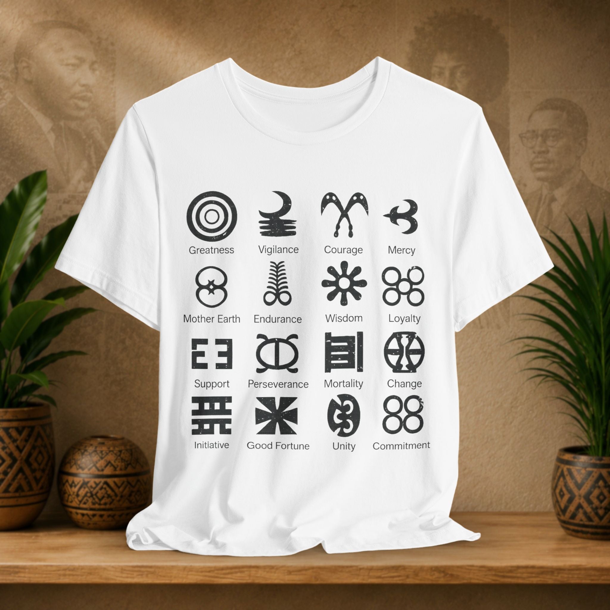 White t-shirt with black symbols and text on a wooden surface with plants and a textured wall in the background