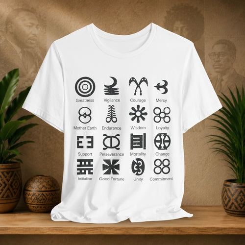 White t-shirt with black symbols and text on a wooden surface with plants and a textured wall in the background