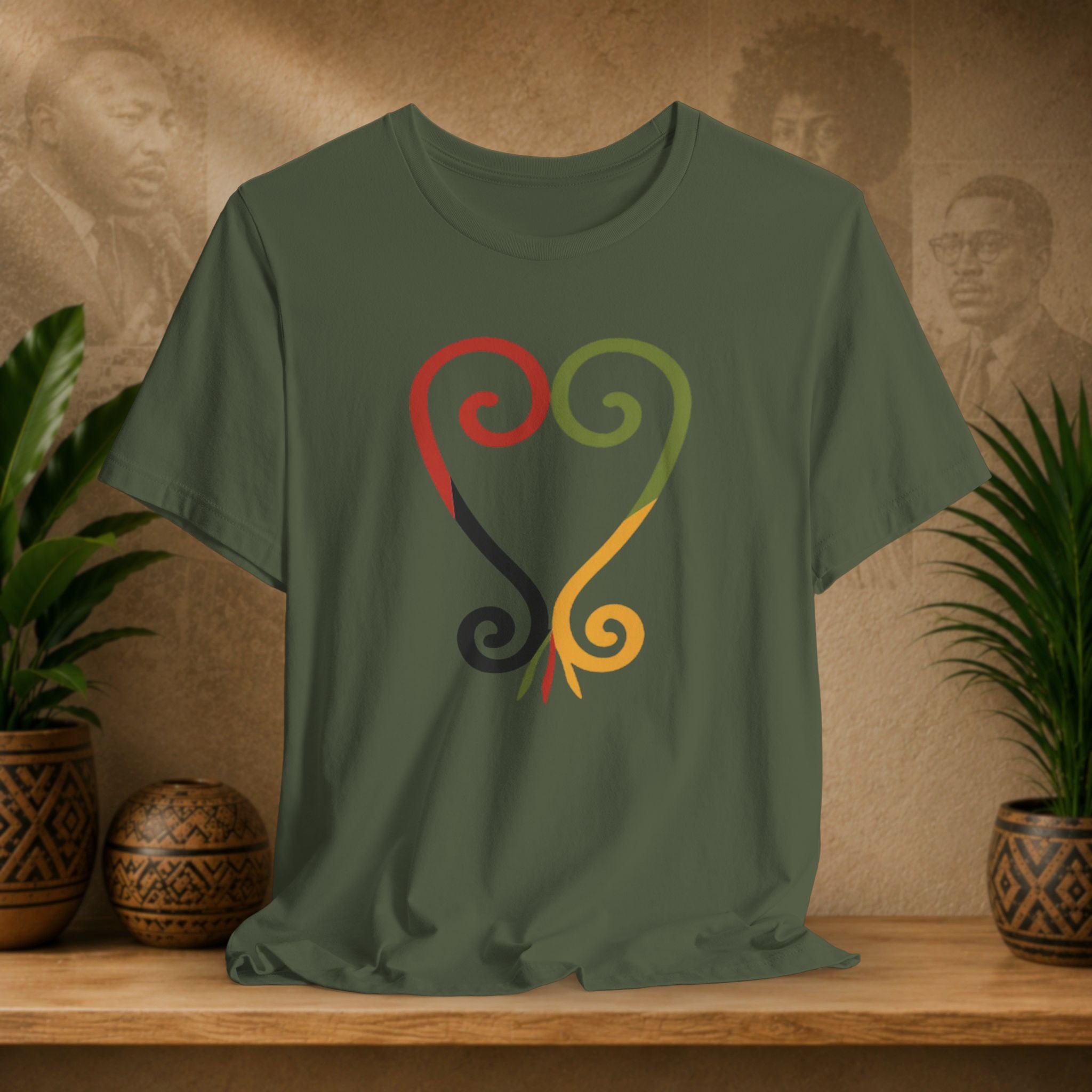 Green t-shirt with colorful design on a wooden surface with plants and decorative items.