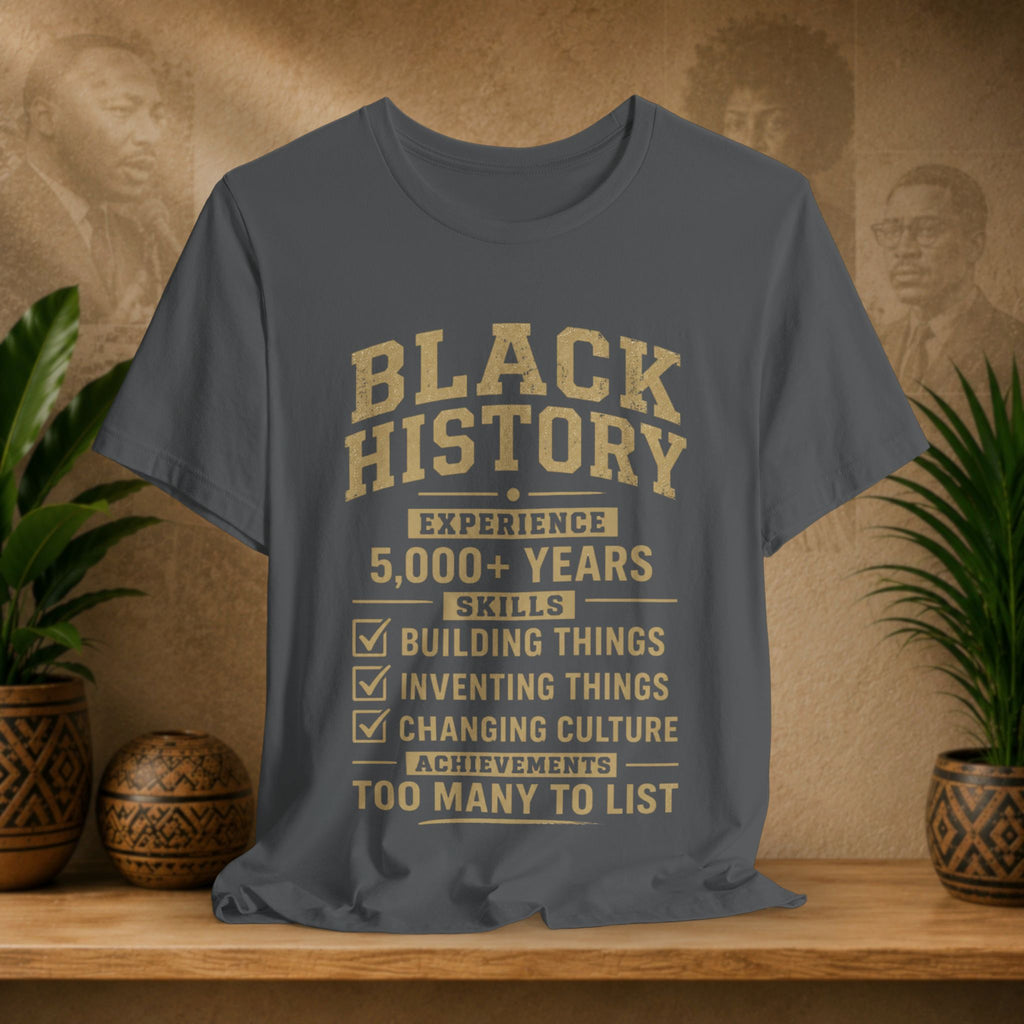 Gray t-shirt with 'Black History' text on a wooden shelf with decorative items.