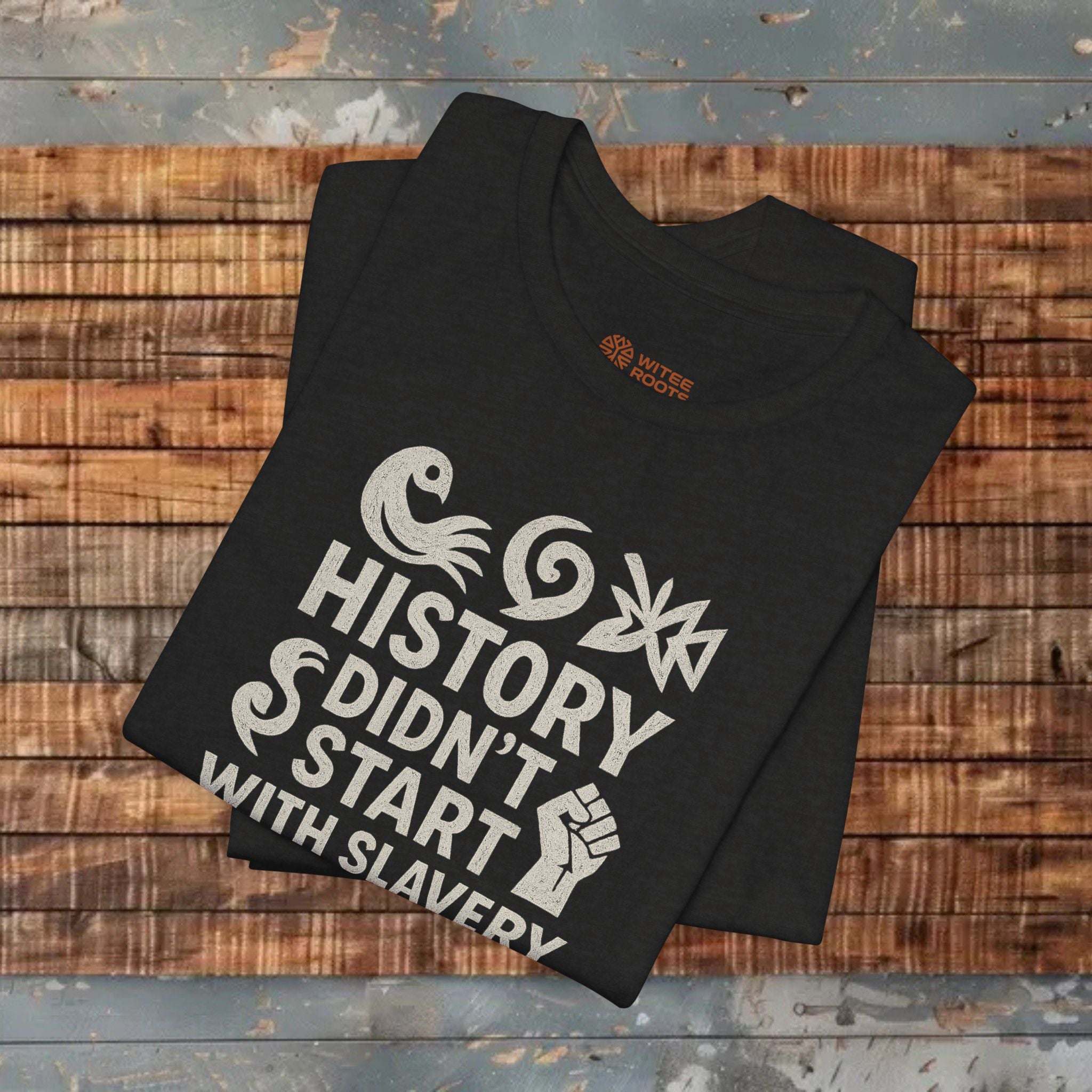 Black t-shirt with white text and graphics on a wooden surface