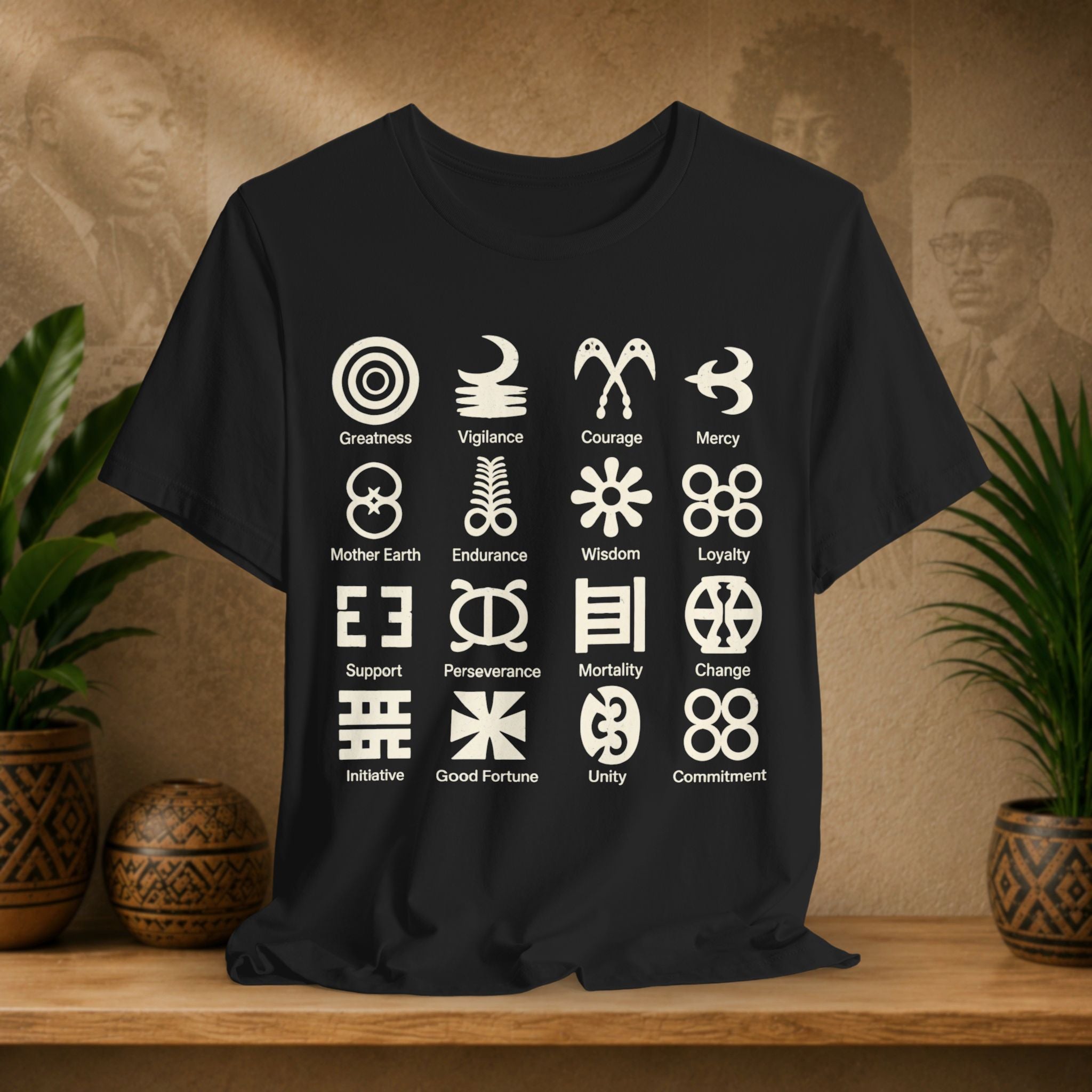 Black t-shirt with white symbols and text on a wooden surface with plants and a textured wall background