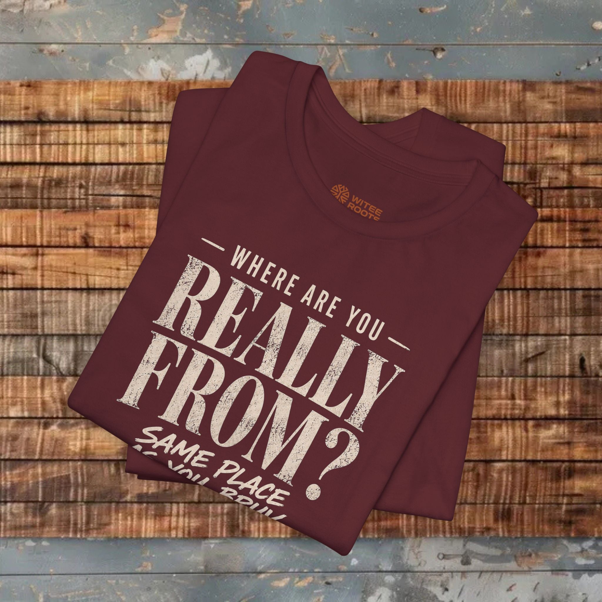 Maroon t-shirt with text on a wooden surface