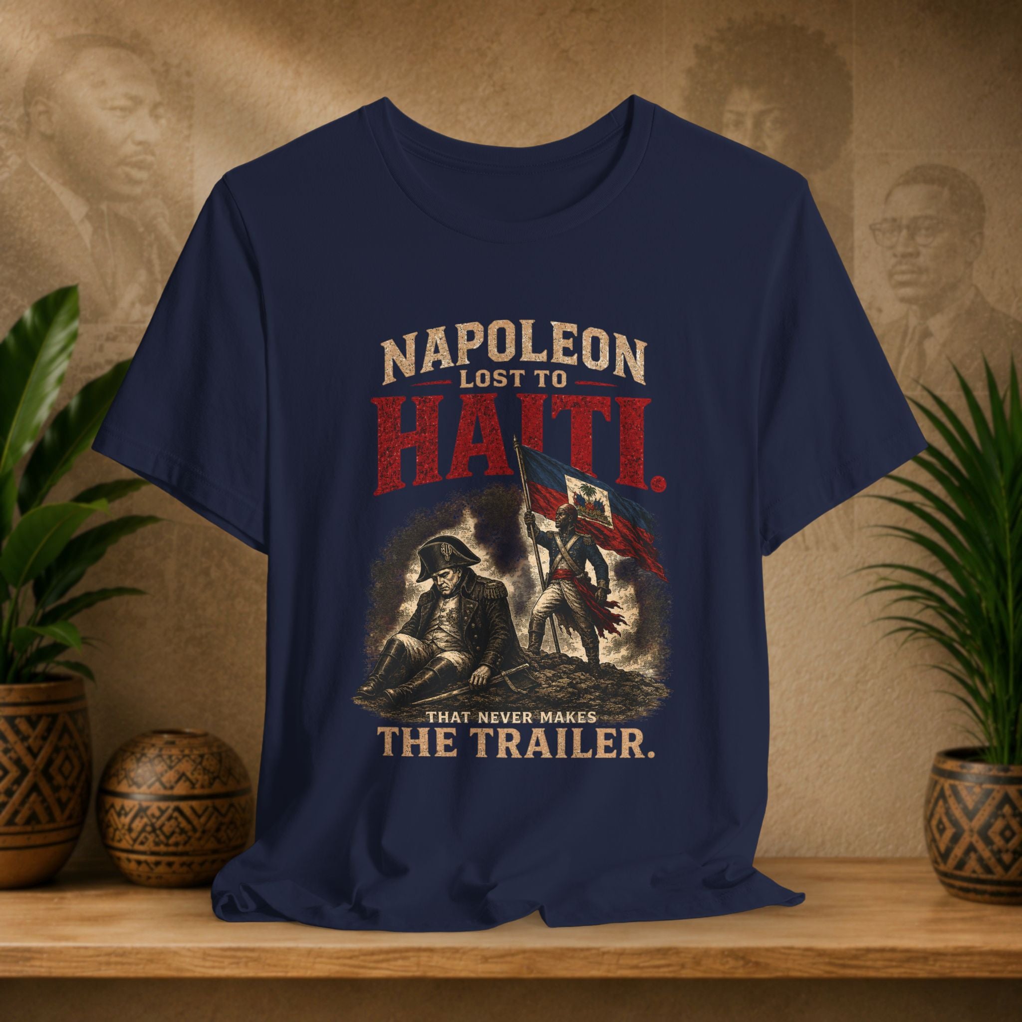 Navy blue t-shirt with historical graphic and text on a wooden surface with plants and a textured wall background.