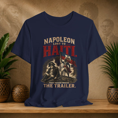 Navy blue t-shirt with historical graphic and text on a wooden surface with plants and a textured wall background.