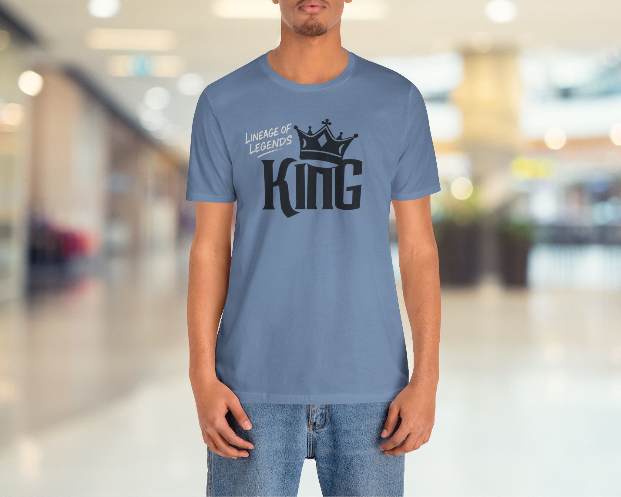 Person wearing a blue t-shirt with 'King' and 'Lineage of Legends' text in a mall setting
