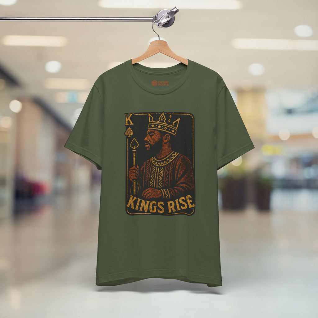 Green t-shirt with a graphic design of a king and 'Kings Rise' text on a hanger in a store.