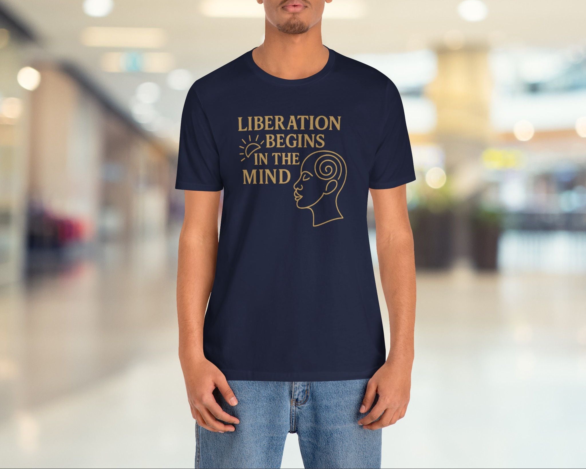 Person wearing a navy blue t-shirt with 'Liberation Begins in the Mind' text and graphic in a blurred indoor setting.