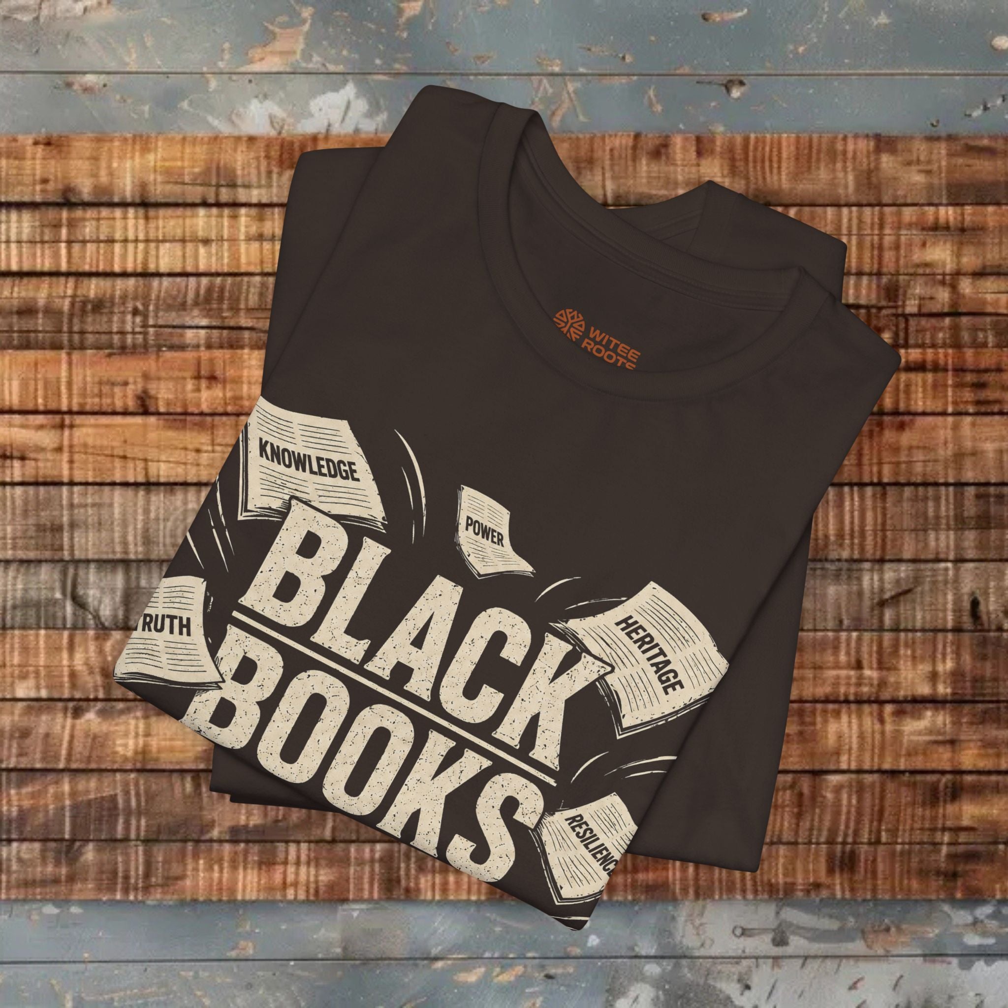 Folded black t-shirt with 'Black Books' design on a wooden surface