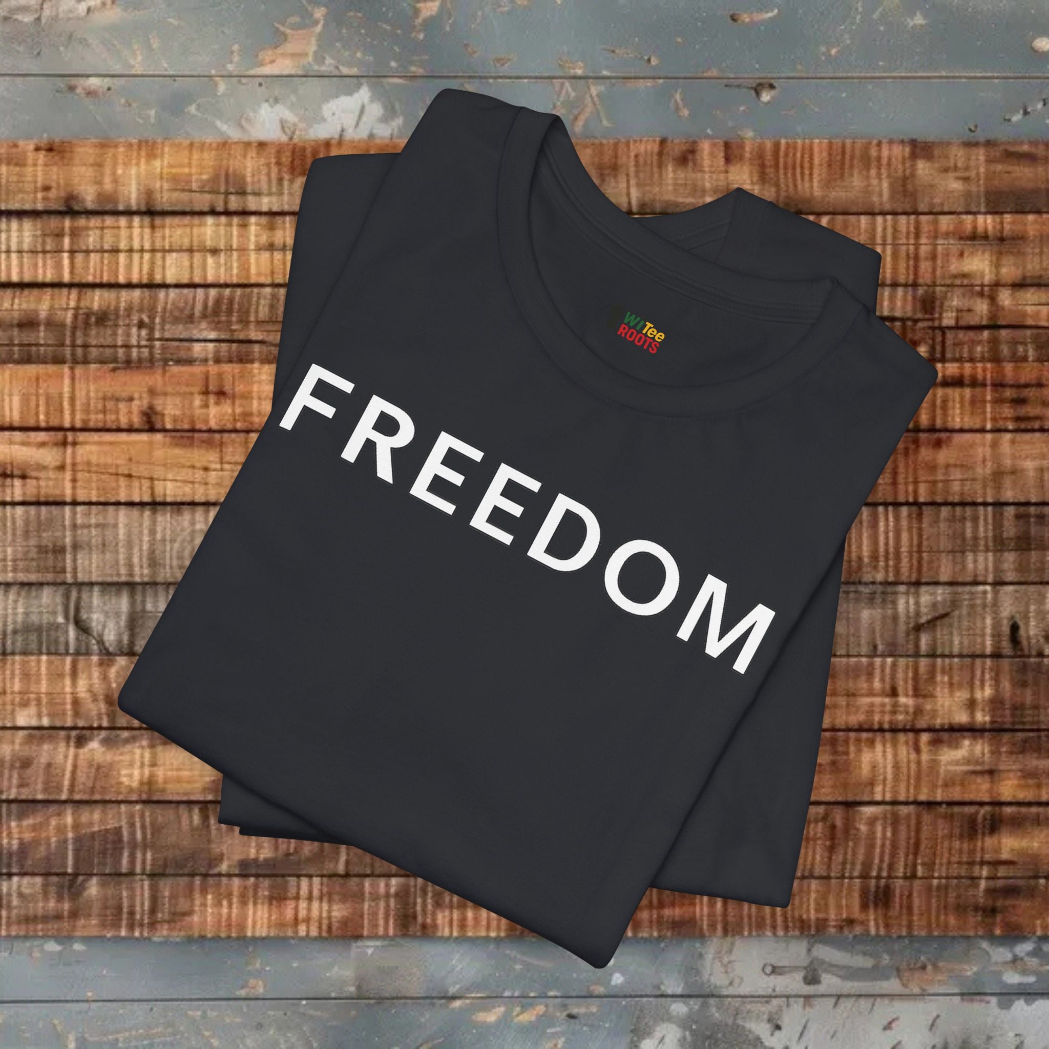 Black sweatshirt with 'FREEDOM' printed on it, folded on a wooden surface