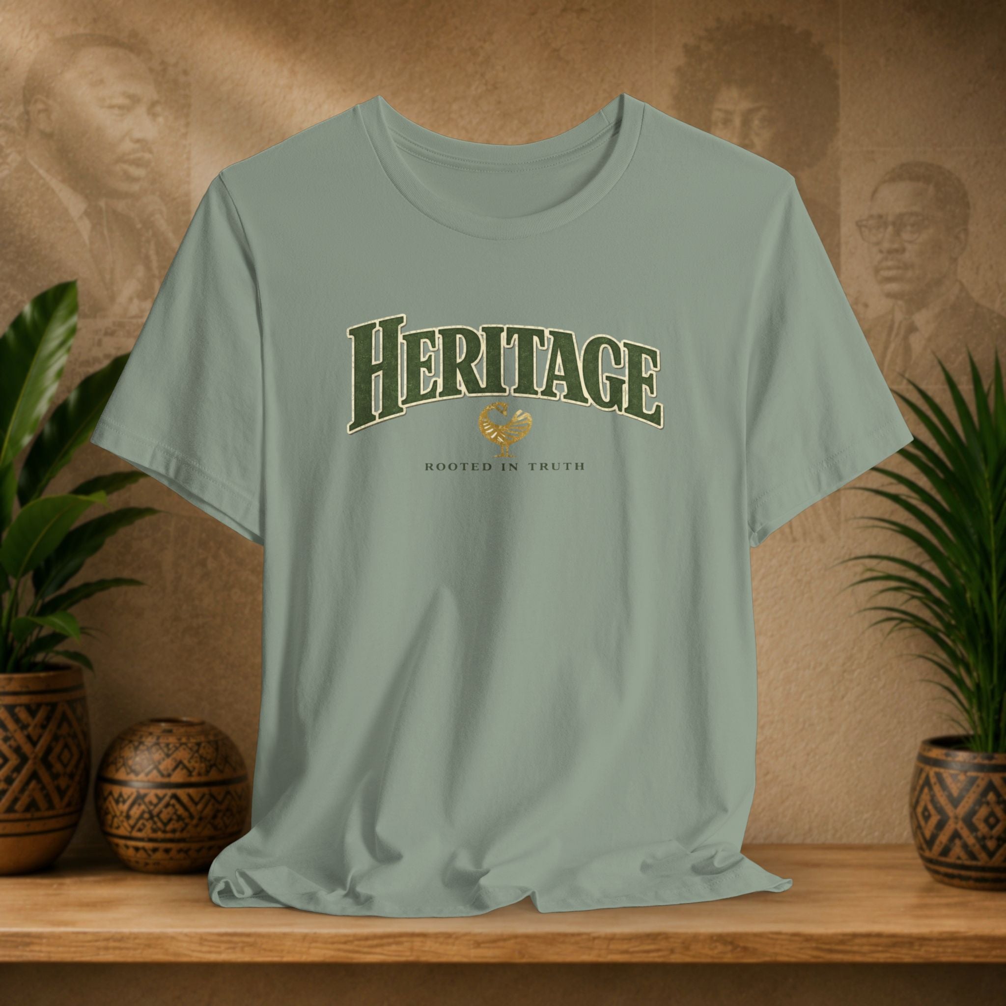 Green t-shirt with 'Heritage' text on a wooden surface with plants and a decorative item in the background.