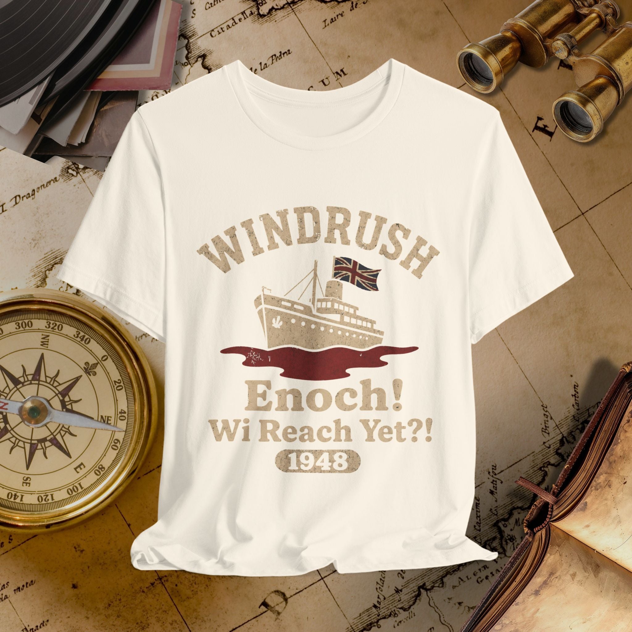 Beige t-shirt with 'Windrush' design featuring a ship and text on a vintage map background.