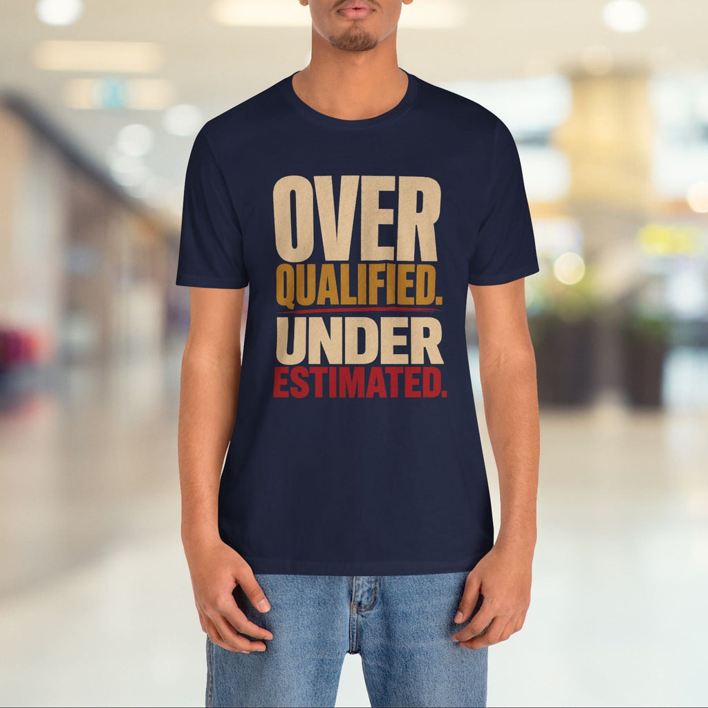 A man wearing a navy blue graphic t-shirt with the text 'OVER QUALIFIED. UNDER ESTIMATED.