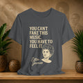 Gray t-shirt with Etta James quote on a wooden surface with plants and wall art in the background