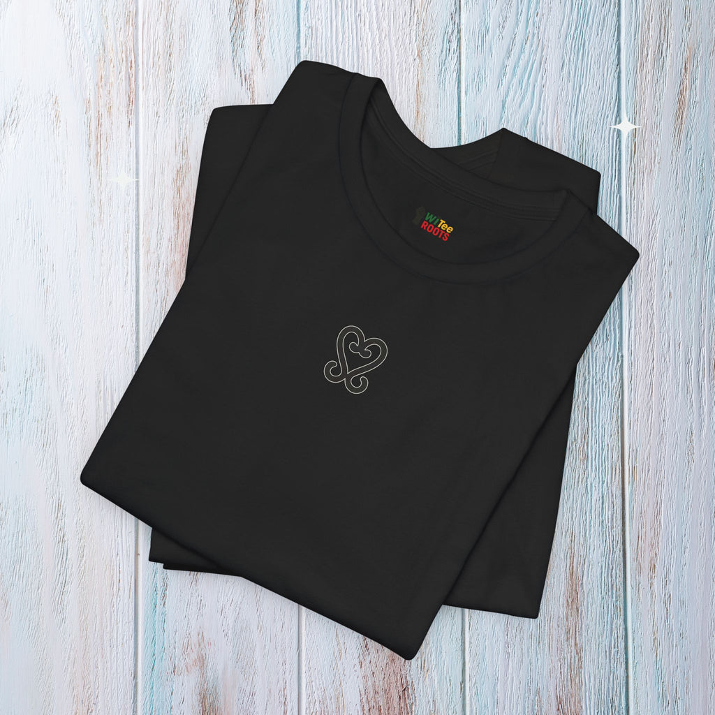 Folded black sweatshirt with a heart design on a light wooden surface