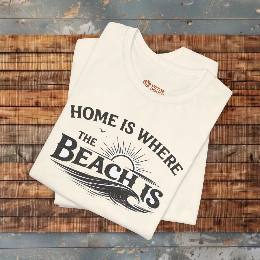 Stack of folded t-shirts with 'Home is where the beach is' text on a wooden surface