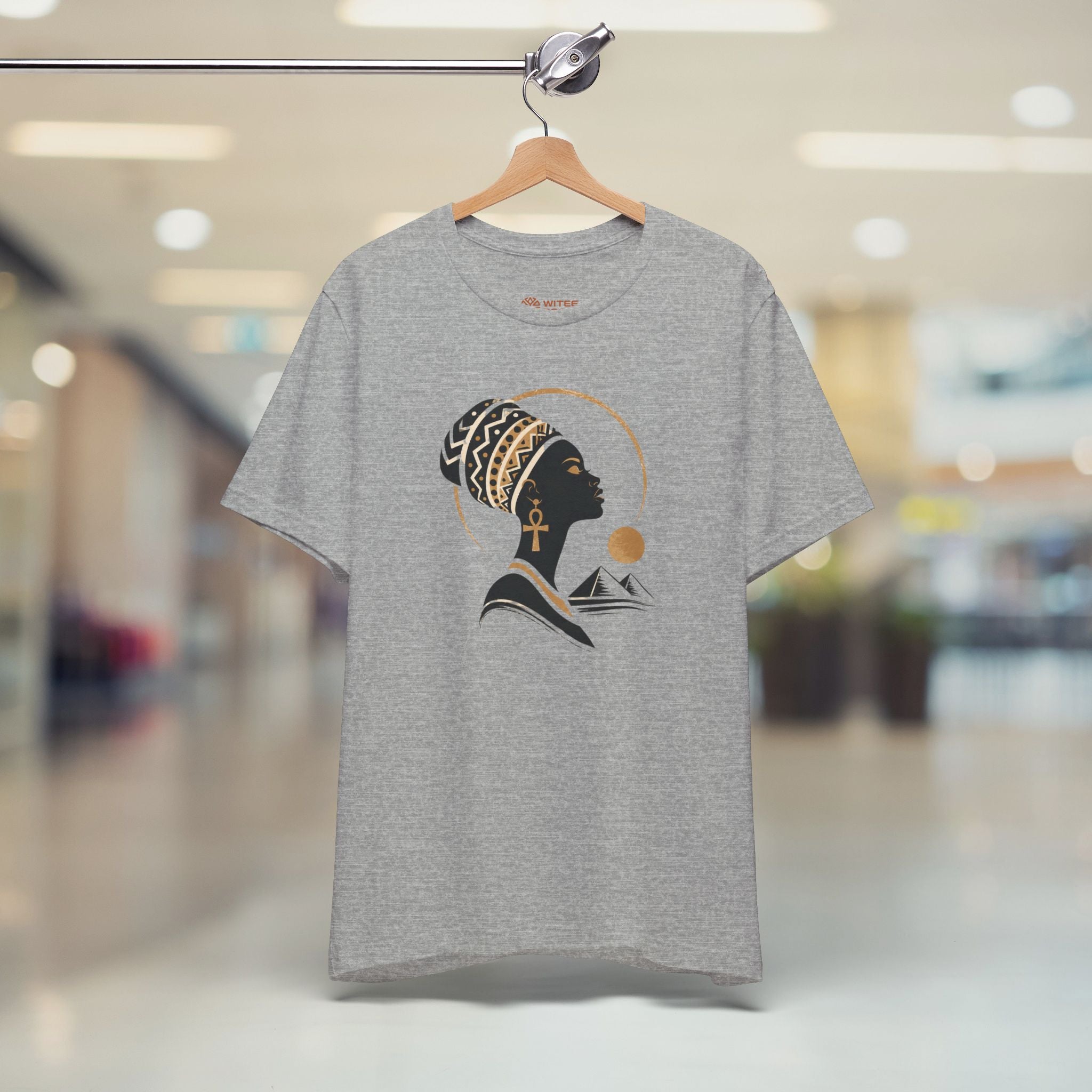 Gray t-shirt with a graphic design of a woman's profile on a hanger in a store.