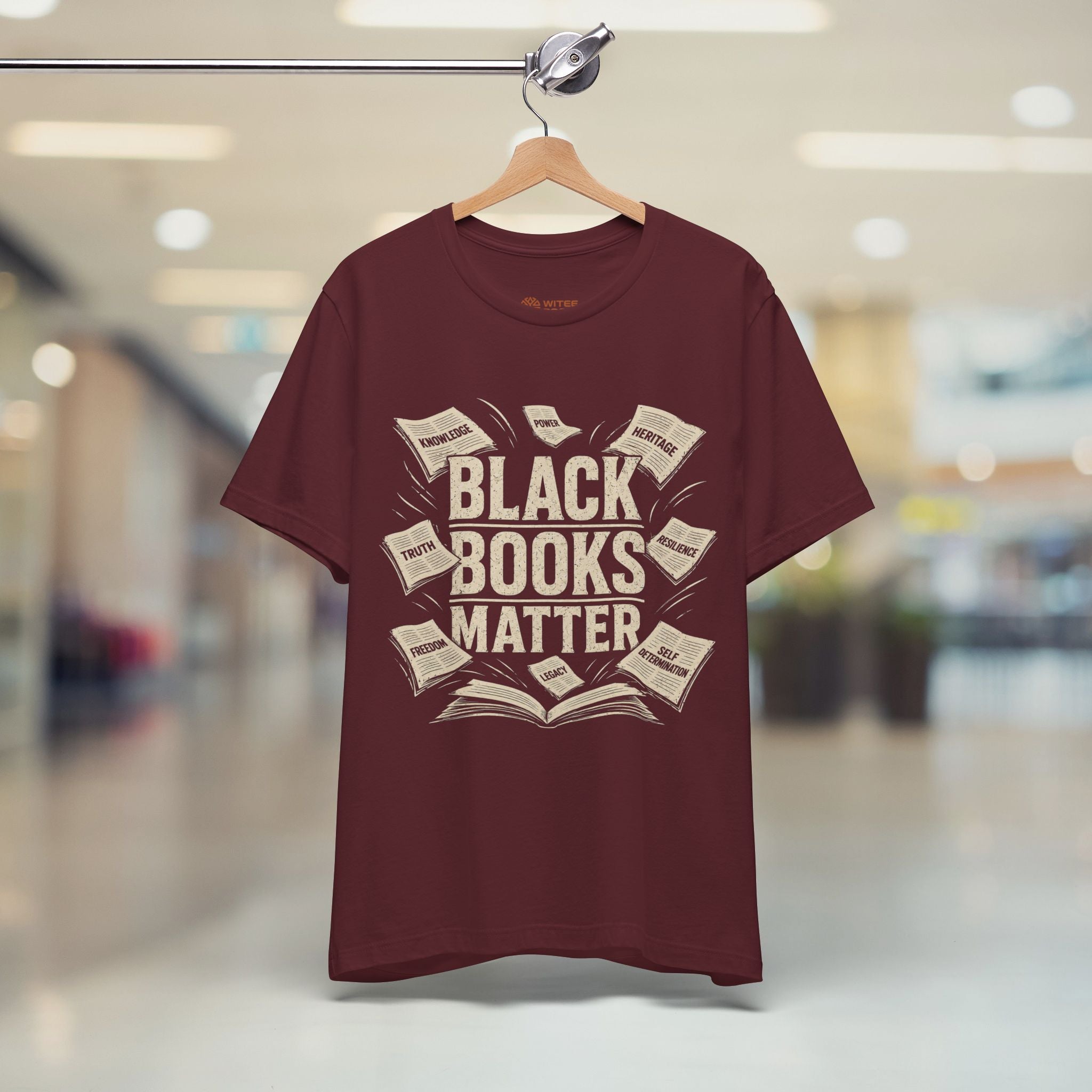 Maroon t-shirt with 'Black Books Matter' text on a hanger in a store setting