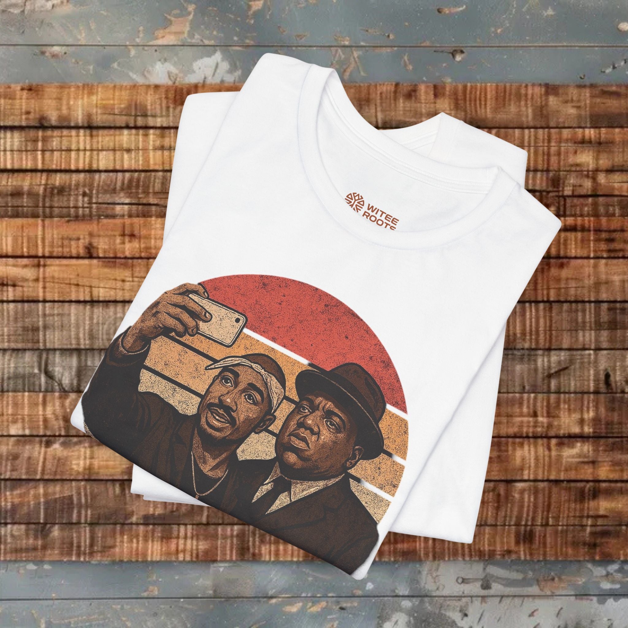 White t-shirt with graphic design of two men taking a selfie on a wooden surface