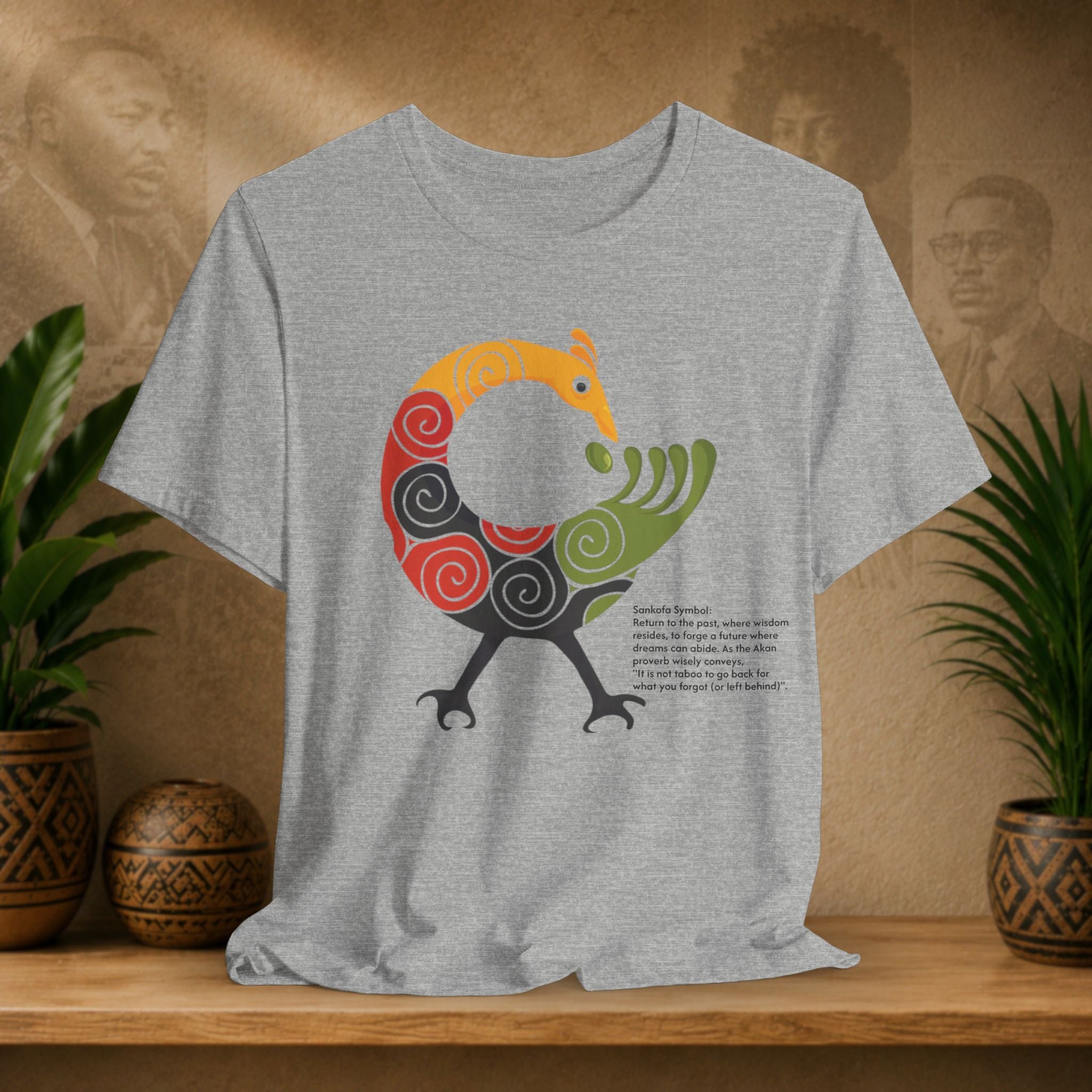 Gray t-shirt with a colorful graphic design on a wooden shelf with plants and decorative items.