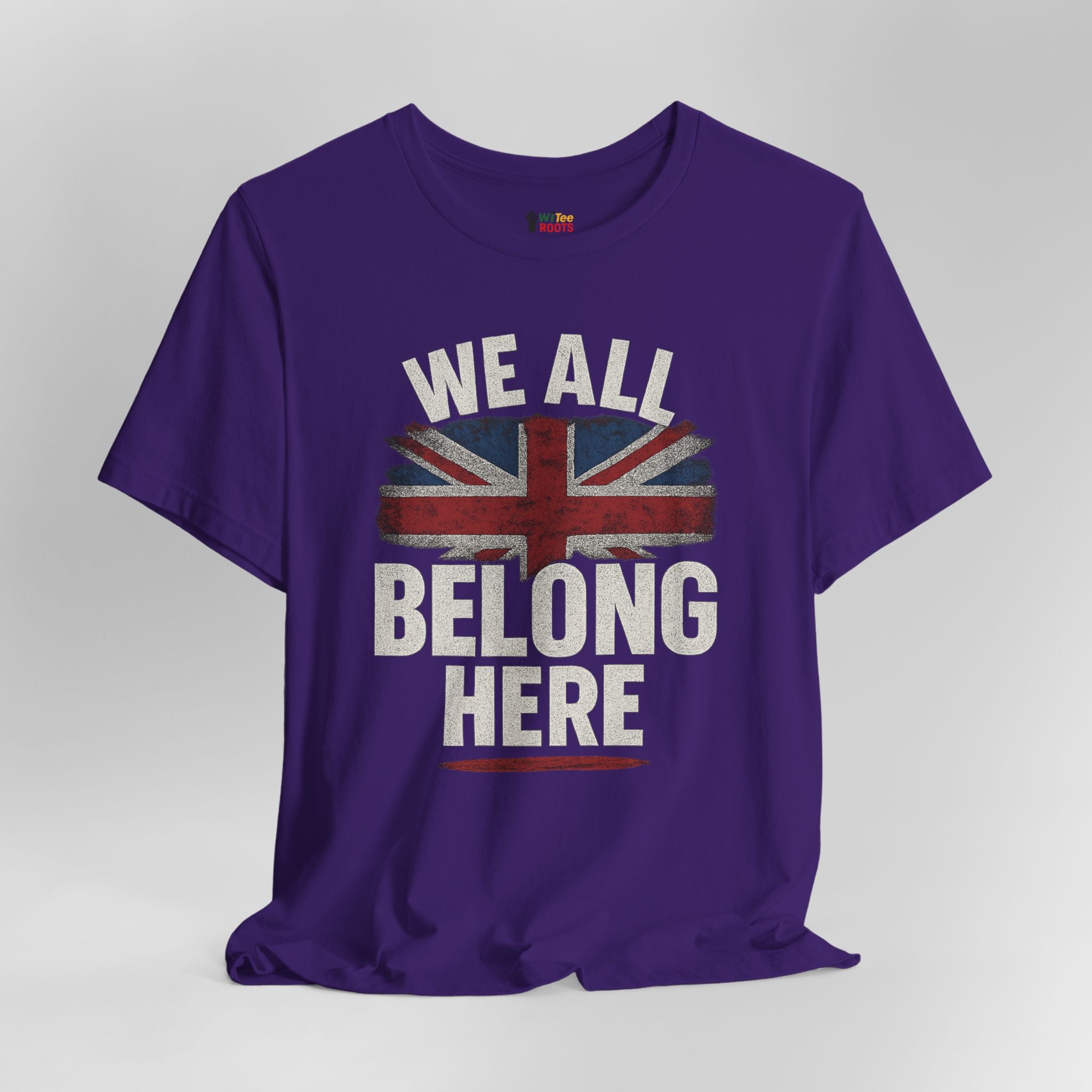 Purple t-shirt with a Union Jack design and text 'WE ALL BELONG HERE' on a gray background