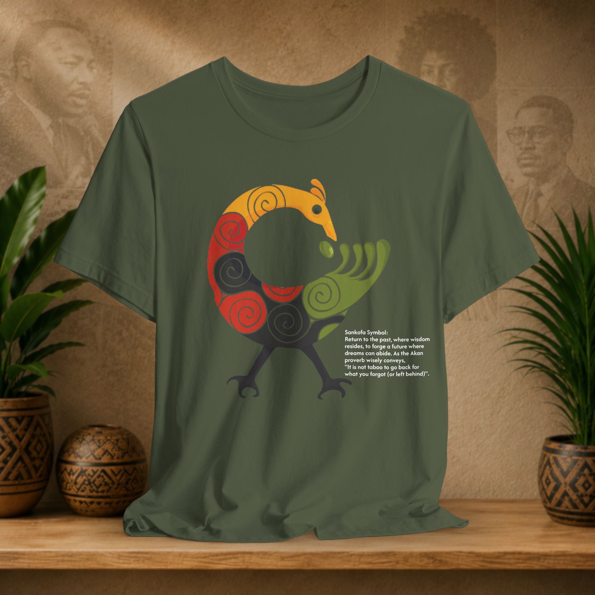 Green t-shirt with a colorful abstract design on a wooden surface with plants and a textured wall background.