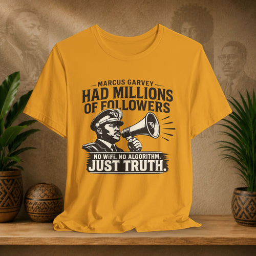 Yellow t-shirt with a graphic and text on a wooden surface with plants and a textured wall in the background