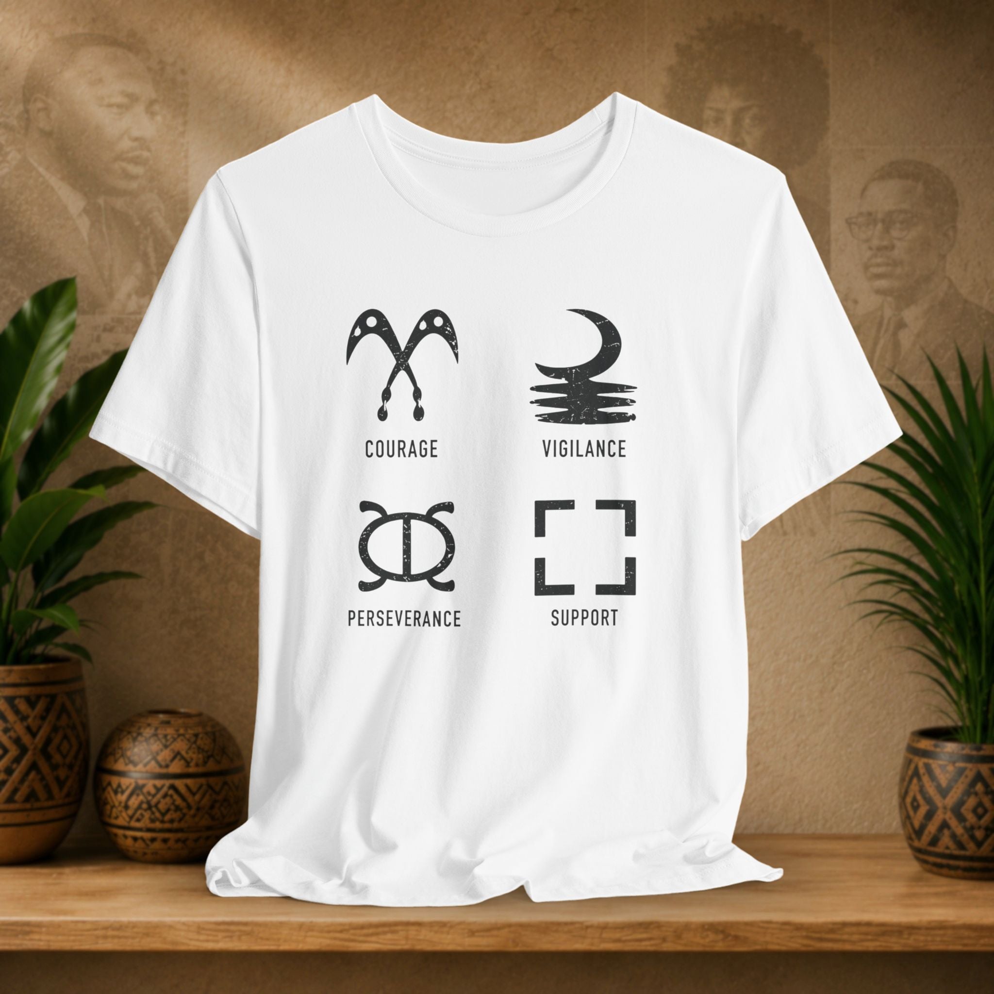 White t-shirt with black symbols and text on a wooden surface with plants and a textured wall background