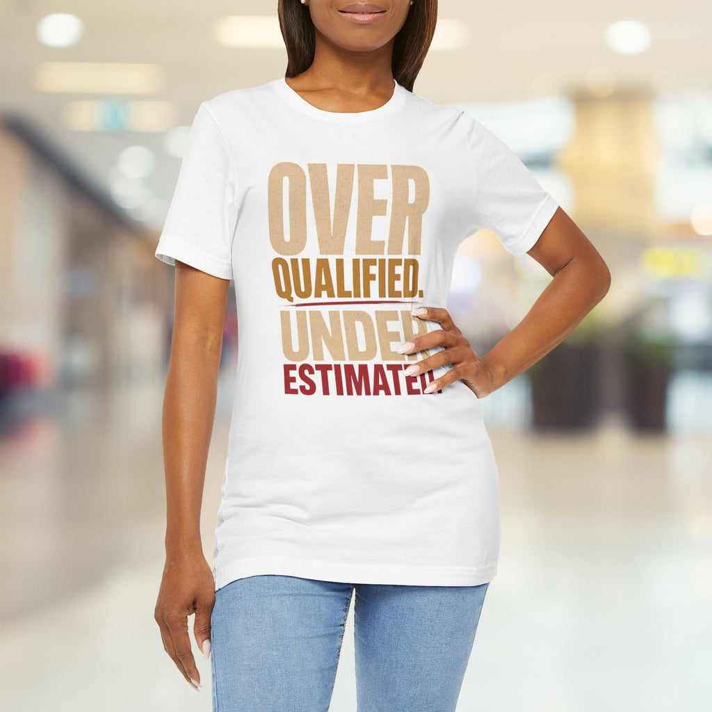 A woman wearing a white graphic t-shirt with the text 'OVER QUALIFIED. UNDER ESTIMATED.