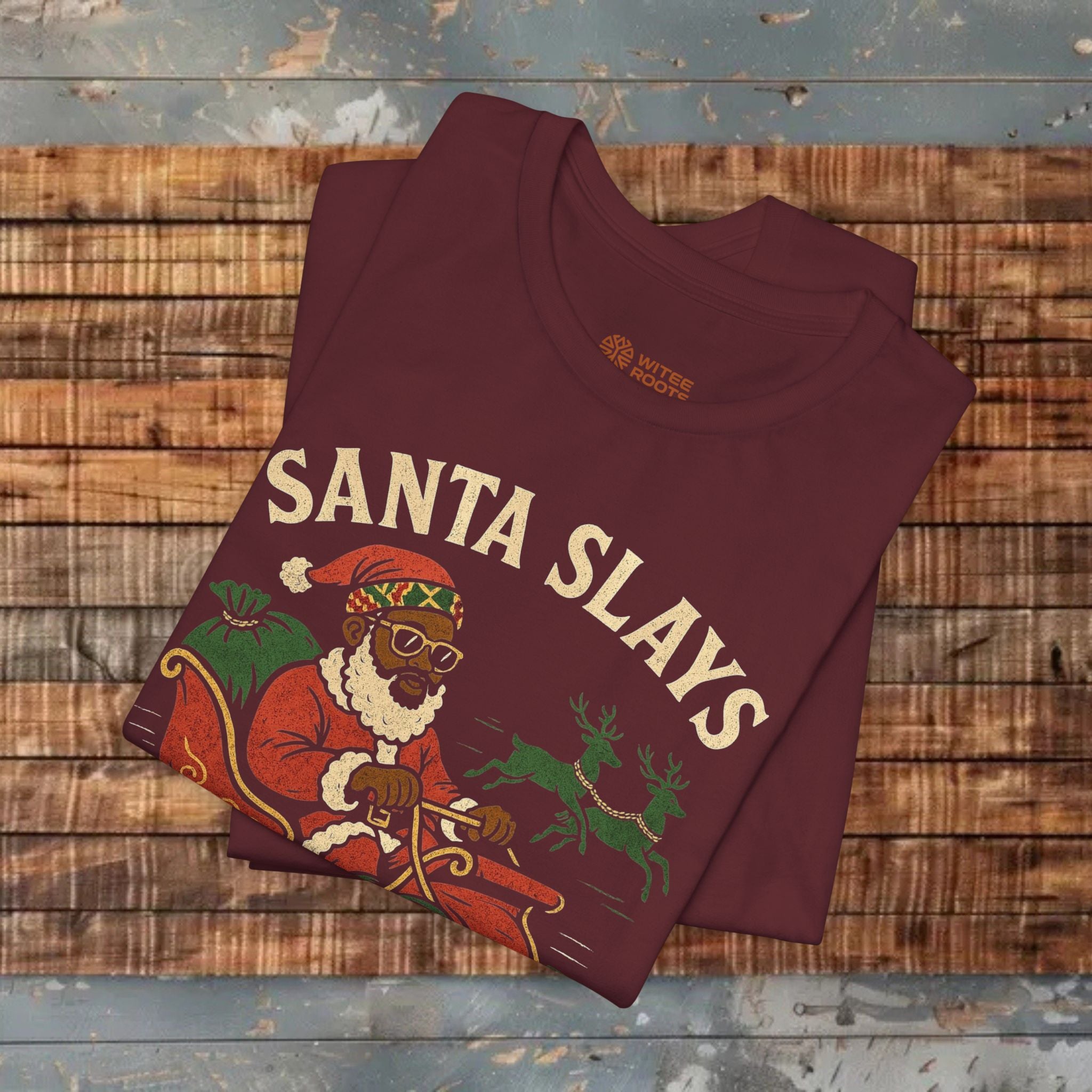 Maroon t-shirt with 'Santa Slays' graphic on a wooden surface