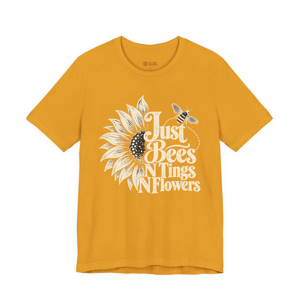 A mustard yellow short-sleeve t-shirt with a graphic print of a sunflower, a bee, and the text 'Just Bees N Tings N Flowers' in white and black, displayed on a solid white background.