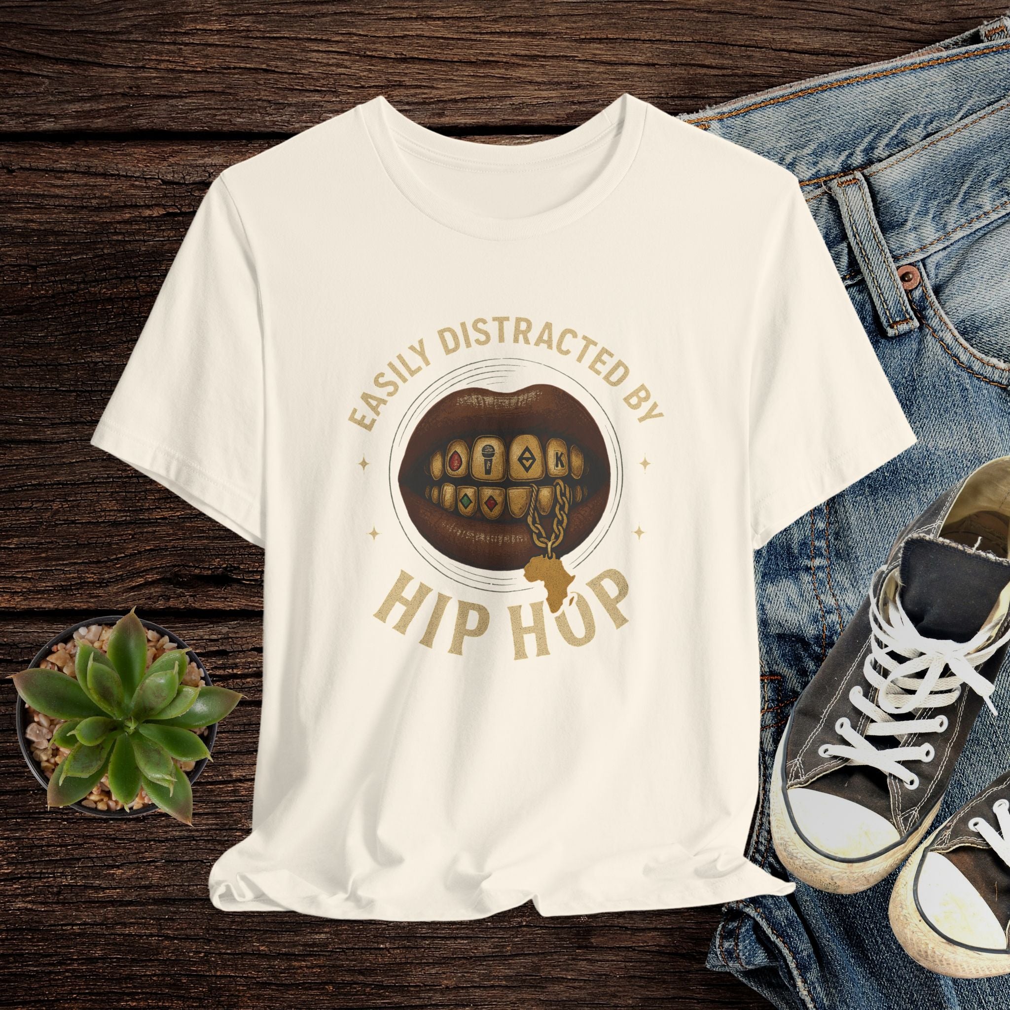 White t-shirt with graphic design and text on a wooden surface with jeans and sneakers.