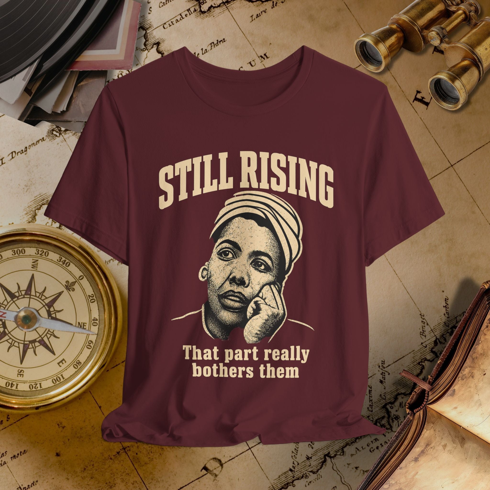 Maroon t-shirt with graphic design and text on a vintage map background