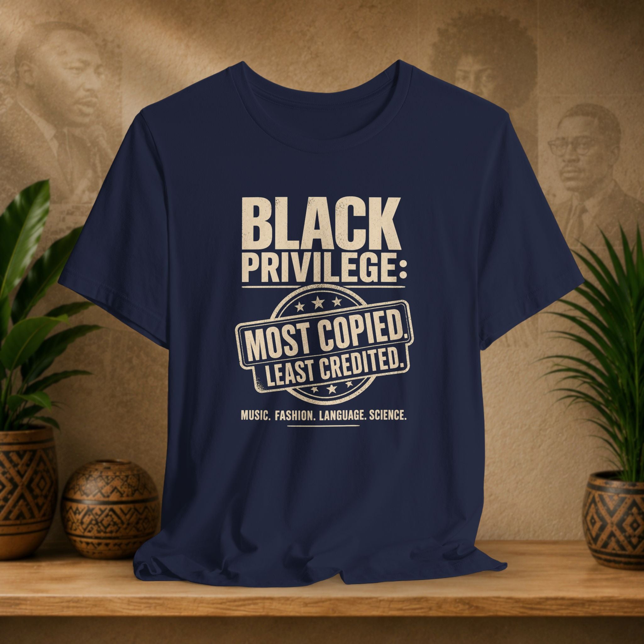 Navy blue t-shirt with white text on a wooden surface with plants and a textured wall background