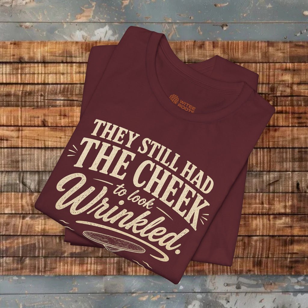 Maroon t-shirt with humorous text design on a wooden surface