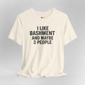 Cream t-shirt with text 'I LIKE BASHMENT AND MAYBE 3 PEOPLE' on a gray background