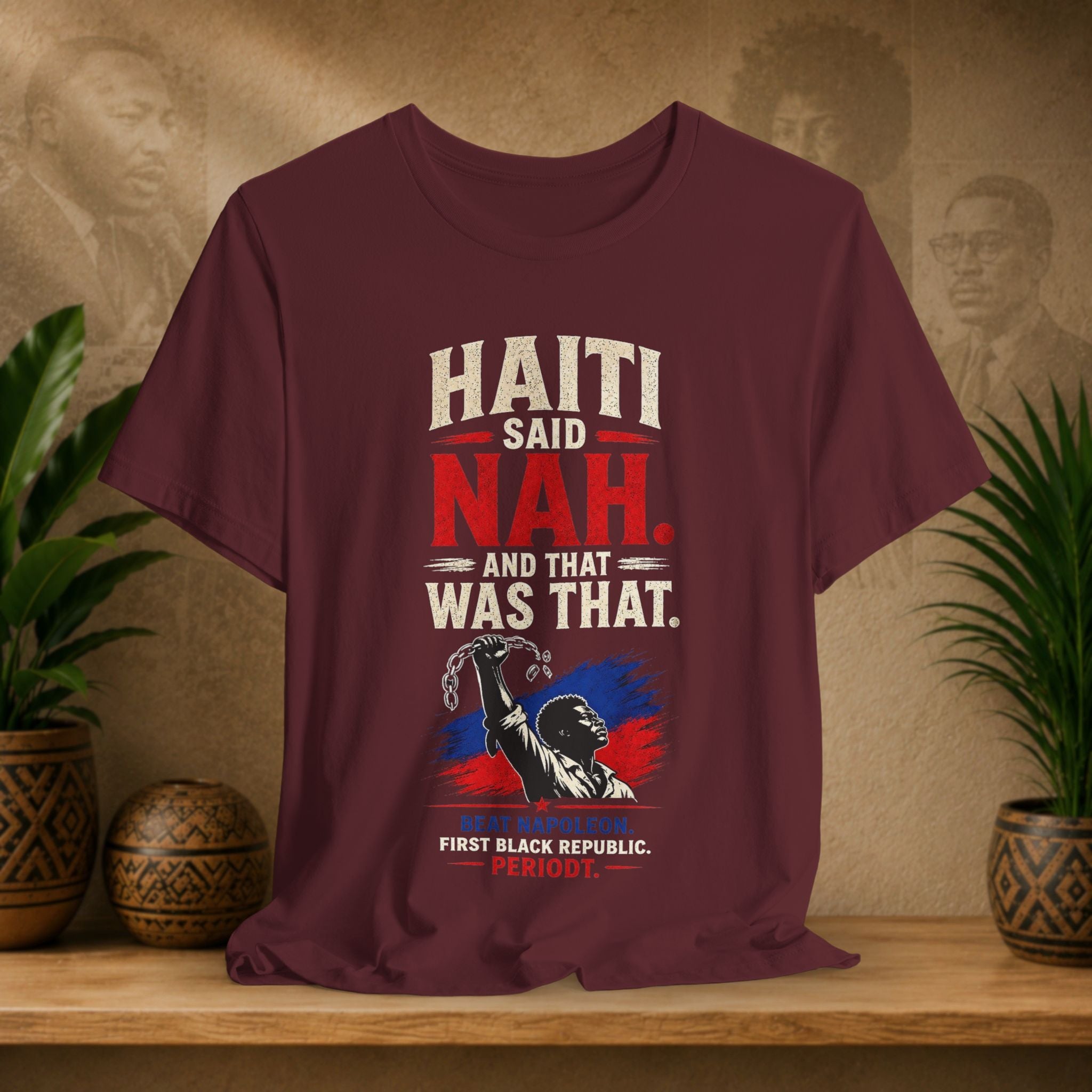 Maroon t-shirt with political graphic and text on a wooden surface with decorative plants.