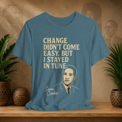 Blue t-shirt with text and a portrait on a wooden surface with plants and a wall in the background