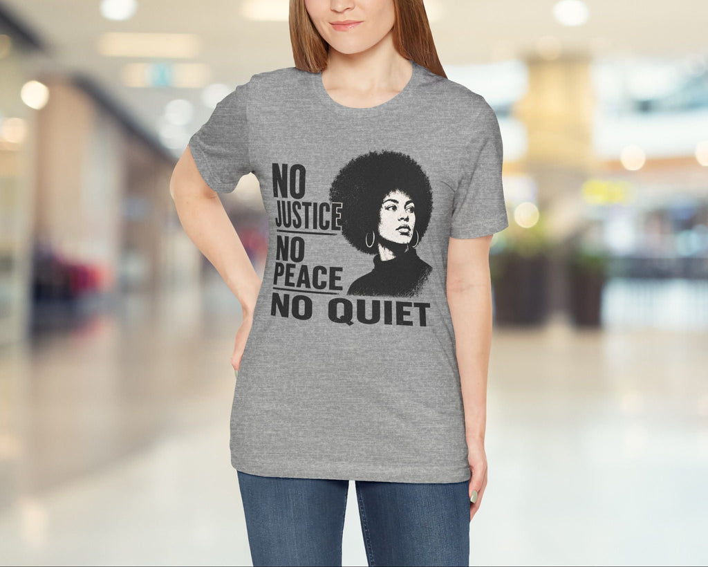 Woman wearing a gray t-shirt with a graphic and text in a blurred indoor setting