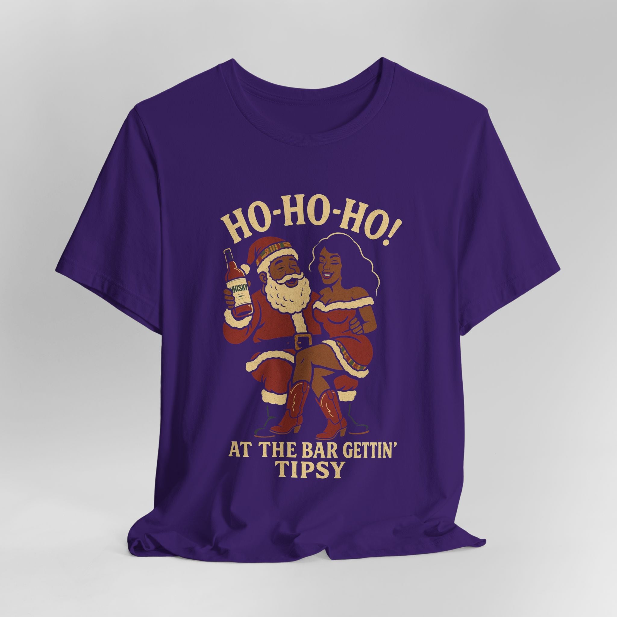 Purple t-shirt with a graphic of Santa and a woman holding drinks, with text 'Ho-Ho-Ho! At the bar gettin' tipsy' on a gray background.