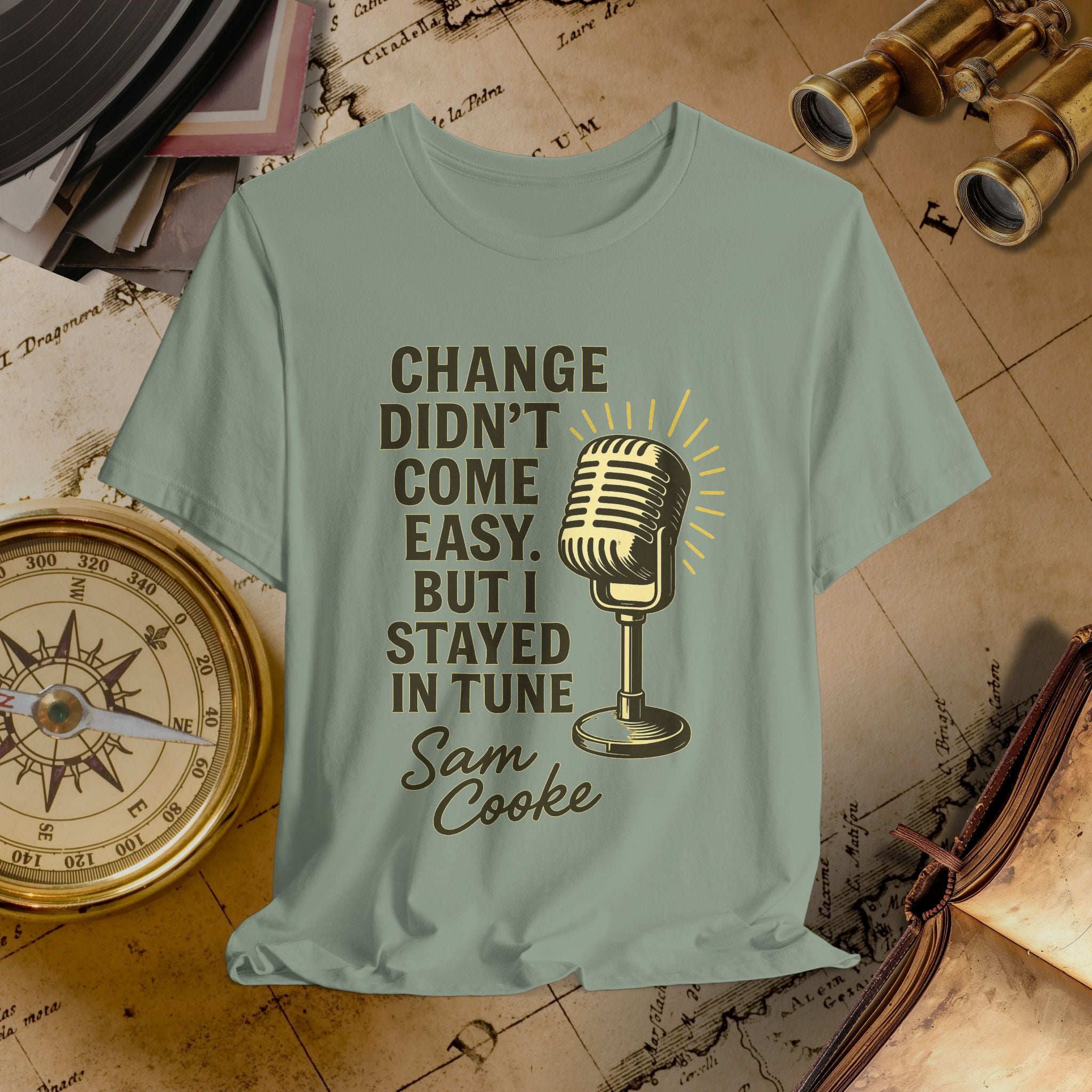 Light green t-shirt with microphone graphic and text on a vintage map background