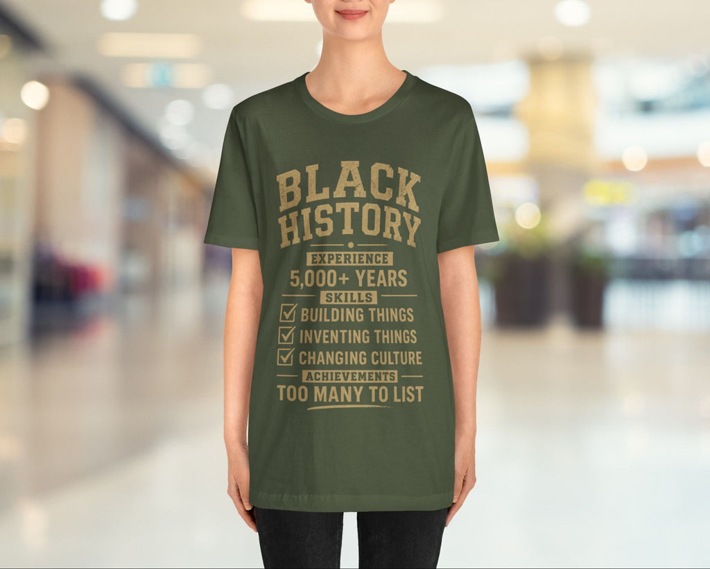 Person wearing a green t-shirt with 'Black History' text in a blurred indoor setting